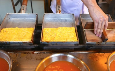 An Absolute Must-Try for Egg Lovers! At Tokyo’s Tsukiji Market You Can Eat Fried and Fluffy, Ready-Made Tamagoyaki, Skewered on the Spot! Check Out the Artisanal Skills of the Chef as He Handles Multiple Frying Pans at the Same Time!